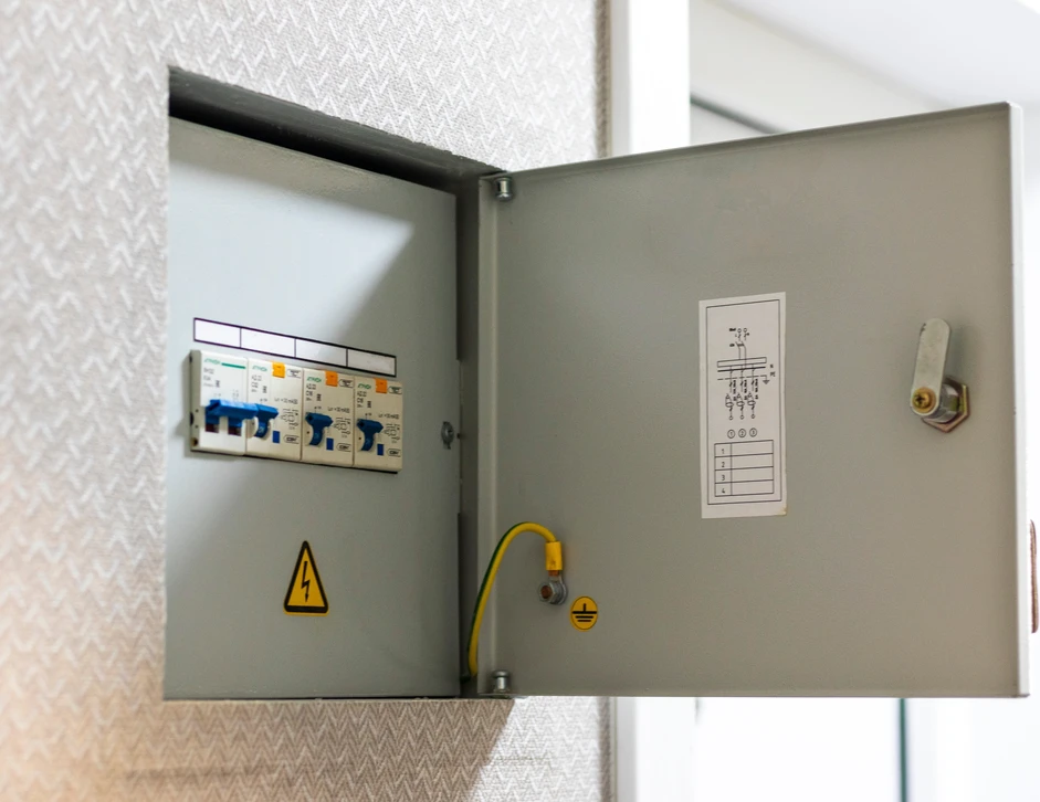 Électricien masculin, barbe courte, installe un luminaire plafonnier sur mur blanc incliné